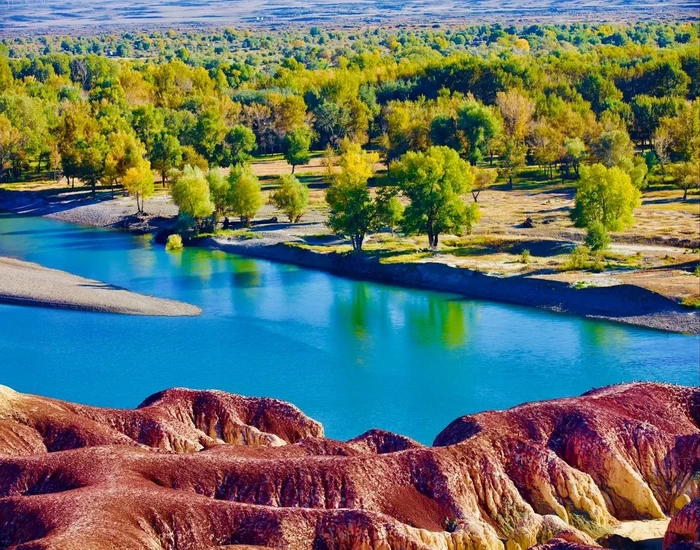 Colorful yardang landforms and the blue Irtysh River at Wucai Beach, Xinjiang.
